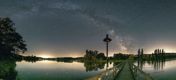 Street by lake against sky at night