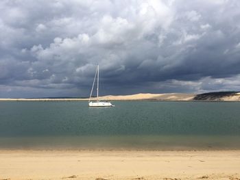 Sailboat sailing in sea against cloudy sky