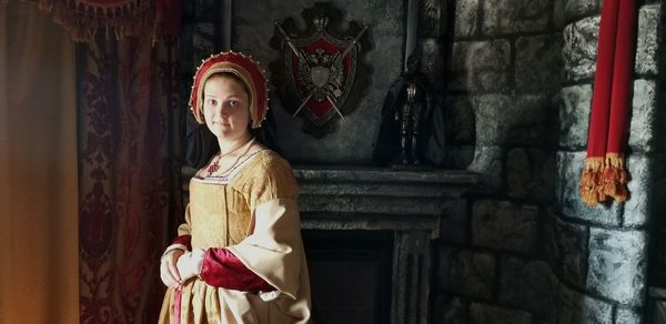 Portrait of woman in traditional clothing standing against wall