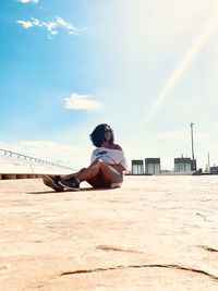 Woman sitting on field against sky