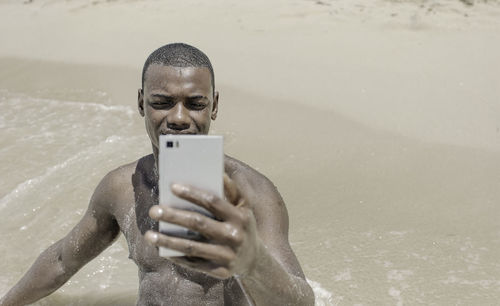 Portrait of young man drinking water at beach