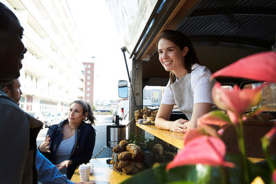 Smiling saleswoman looking at customer while standing in food truck