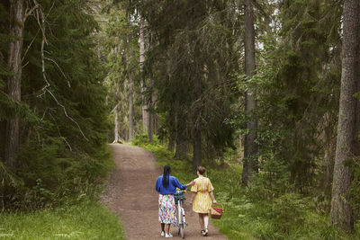 Female couple walking in forest with bicycle