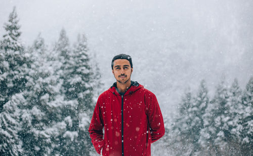 Portrait of smiling young man standing in snow