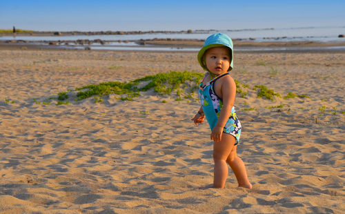 Cute girl looking away while standing on shore of beach