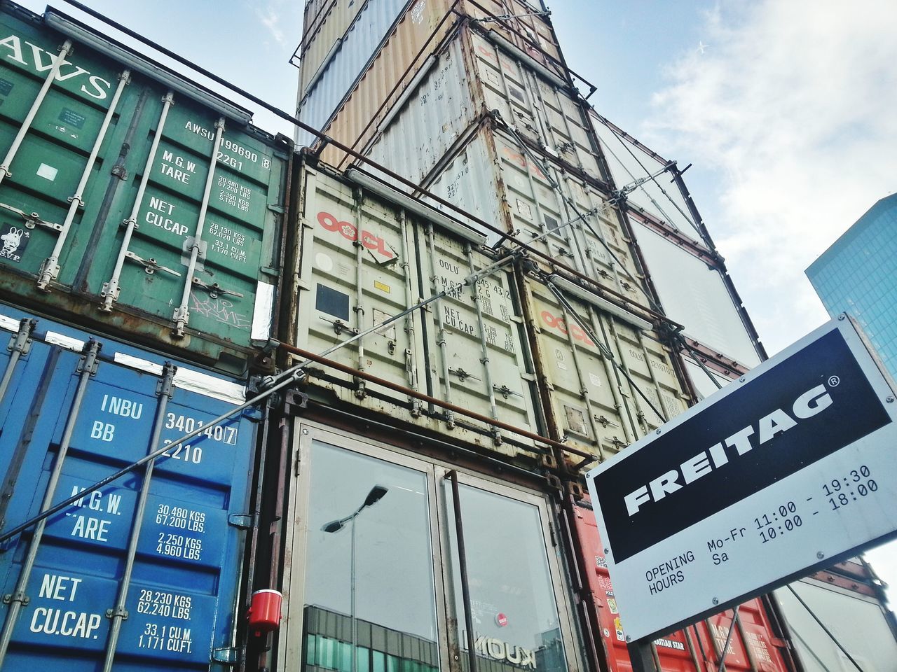 text, architecture, low angle view, building exterior, western script, built structure, communication, city, information, non-western script, sky, capital letter, building, information sign, sign, day, window, guidance, modern, road sign