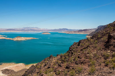 Scenic view of sea and mountains against blue sky