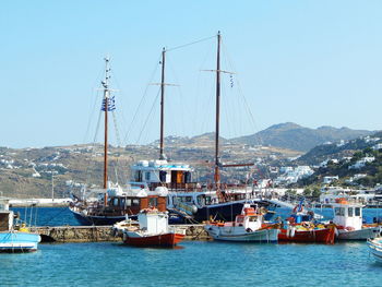 Sailboats moored at harbor against clear sky