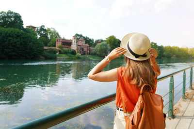 Traveler girl holding her hat discovering hidden castle in the park