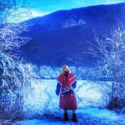 Full length portrait of young woman standing on snow covered landscape