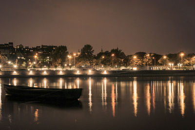 River by illuminated buildings against clear sky at night