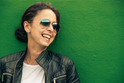 Portrait of smiling man wearing sunglasses against green wall