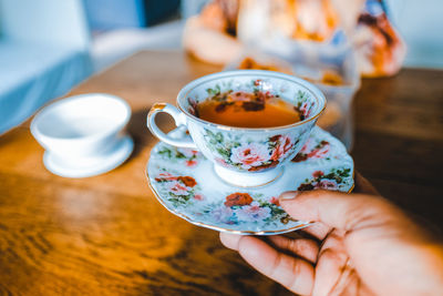 Close-up of person holding tea cup on table