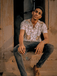 Portrait of young man sitting against old train 