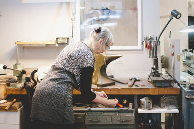 Rear view of senior woman holding drill bit in workshop