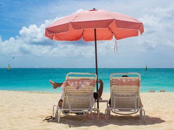 Deck chairs on beach against sky