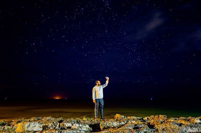 Man standing on rock against star field at night