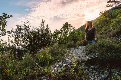 Woman sitting on plants against sky