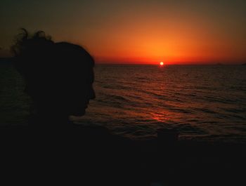 Silhouette woman standing at beach during sunset