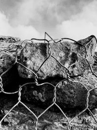 Close-up of barbed wire fence against sky