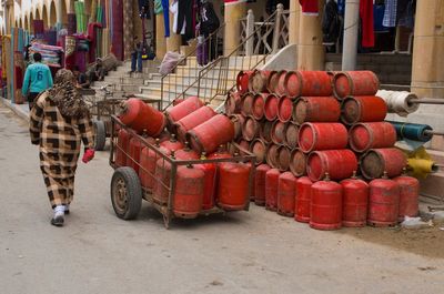 Rear view of woman walking by red gas cylinders on street