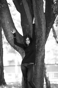Woman standing by tree trunk