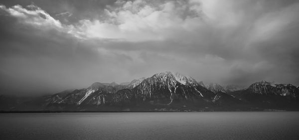 Scenic view of lake by snowcapped mountains against sky