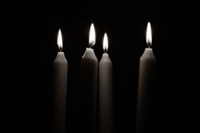 Close-up of candles burning in darkroom