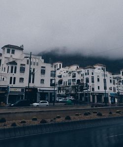 Road by buildings in city against sky