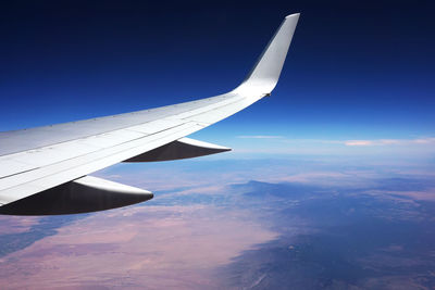Aerial view of airplane wing against blue sky