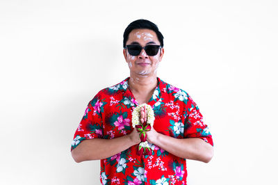 Young man wearing sunglasses while standing against white background