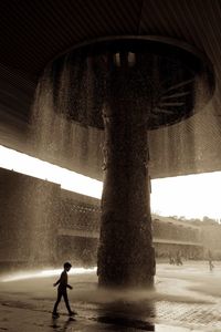 Silhouette man by fountain against sky