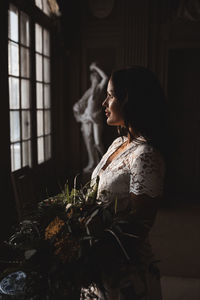 Side view of woman looking at window