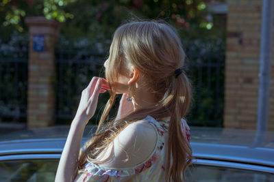 Side view of woman standing by car in city