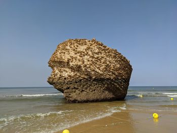 Rock formation on beach against clear sky