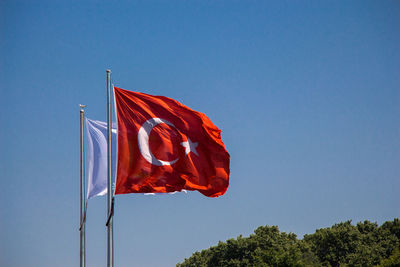 Low angle view of flag against clear blue sky