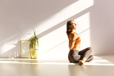 Side view of woman sitting on wall