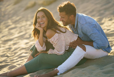 Portrait of smiling woman with boyfriend sitting on beach