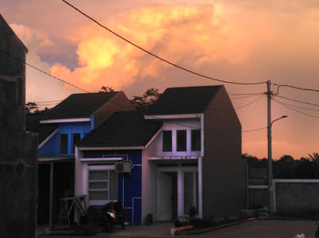 Houses and buildings against sky during sunset