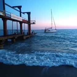 Sailboat in sea against sky during sunset