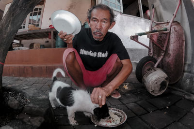 Portrait of senior man feeding puppy outdoors