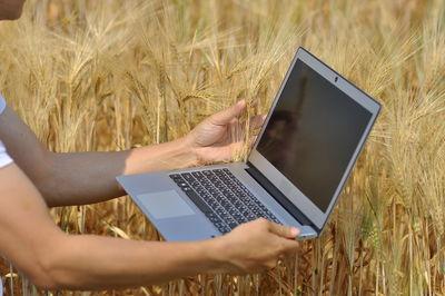 Midsection of woman using mobile phone on field