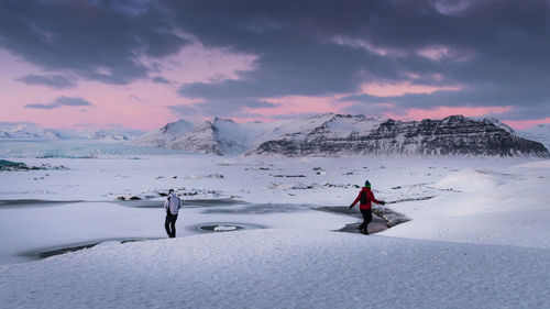 People on snowcapped mountain against sky