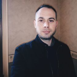 Portrait of young man standing against wall at home