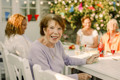 Portrait of happy senior woman sitting at dining table in back yard