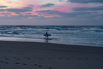 Silhouette man on beach against sky during sunset
