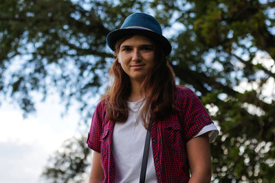 Young woman standing against trees