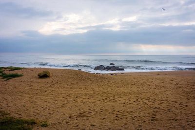 Scenic view of beach against cloudy sky