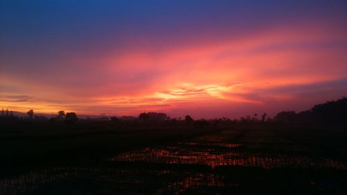 Scenic view of silhouette field against sky during sunset