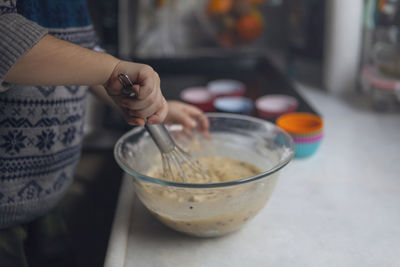 Midsection of woman preparing food in bowl on kitchen counter at home